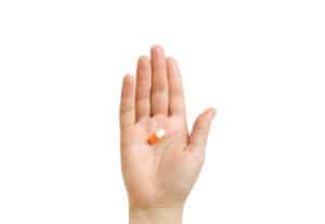 A hand holds a pill to represent the adderall withdrawal timeline. 