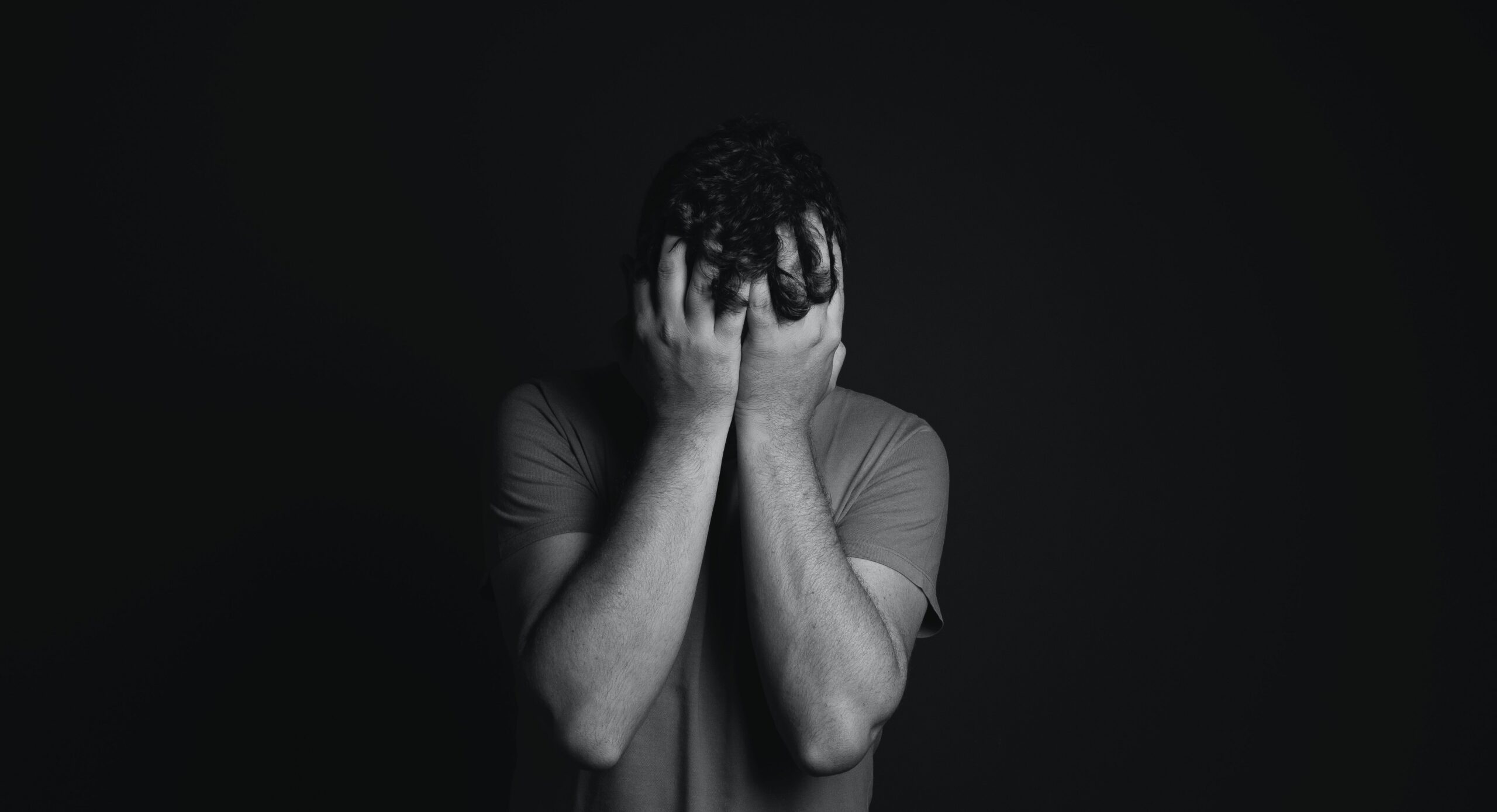 a black and white photo of a person with their head in their hands to represent opioid overdose. .
