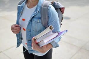 An image of a woman holding a book about Mental Health in College Students