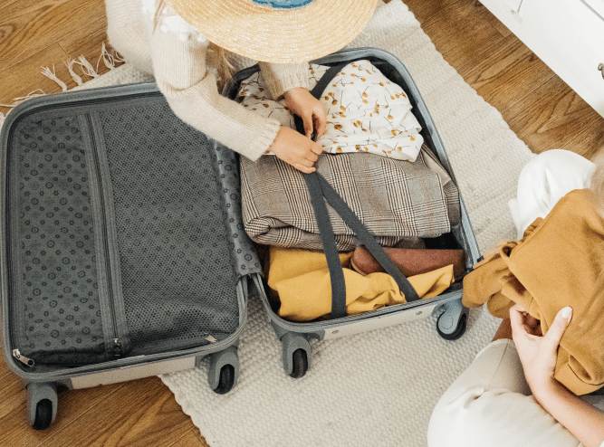 person finishing up packing and closing a suitcase
