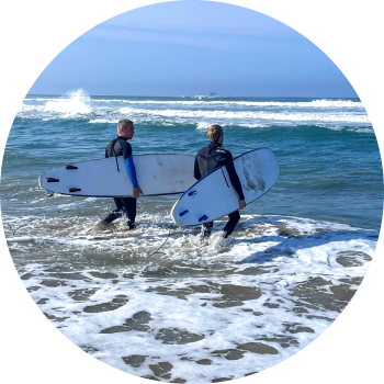 2 surfers walking into the ocean with their surfboards