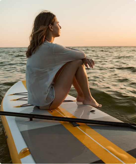 woman sitting on a paddle board on the water