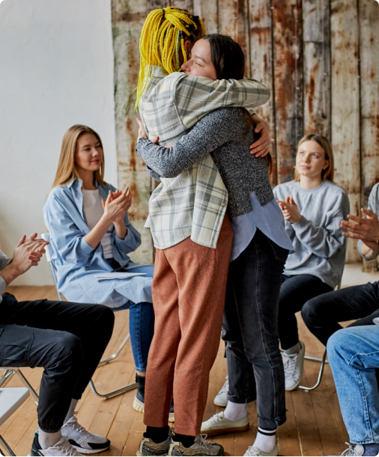 2 people hugging in front of a support group