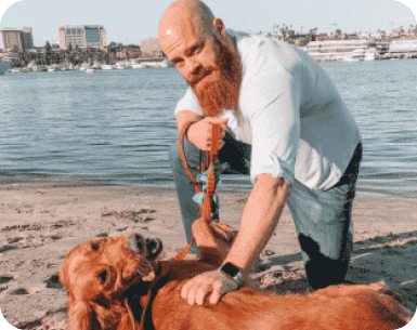 person petting their dog on the beach