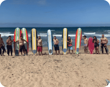 people posing with their surfboards on the beach