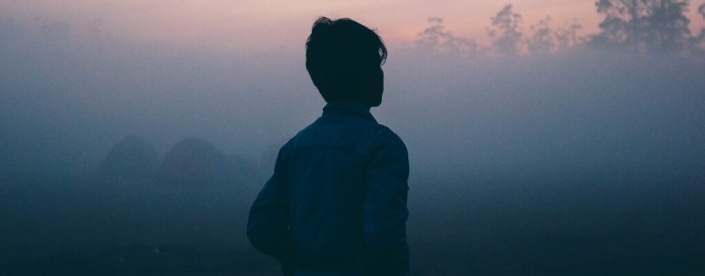A young man is standing against a sunrise to represent klonopin addiction risks and faqs, wondering is klonopin addictive. .