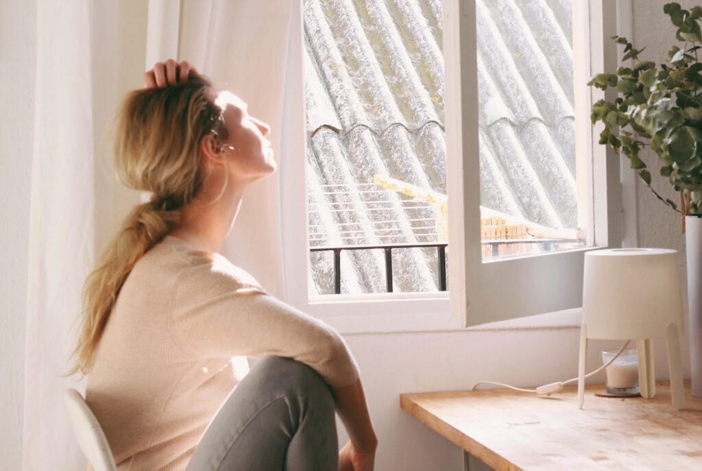 a woman is looking out a window to represent levels of recovery.