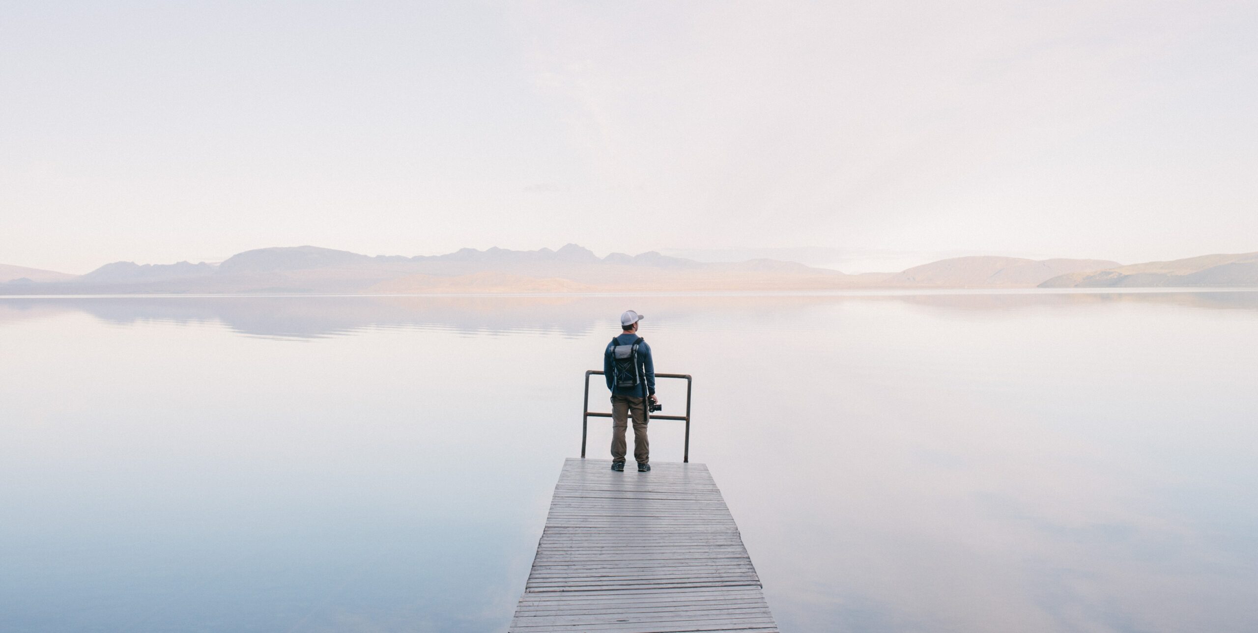 A man stands on a dock on a lake on a foggy day, representing addiction and dopamine: how are addiction and dopamine related?