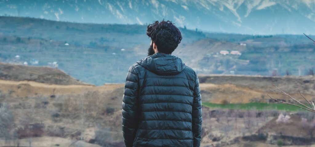 A man stands on a hill looking out at the scenery to represent alcohol withdrawal timeline. 