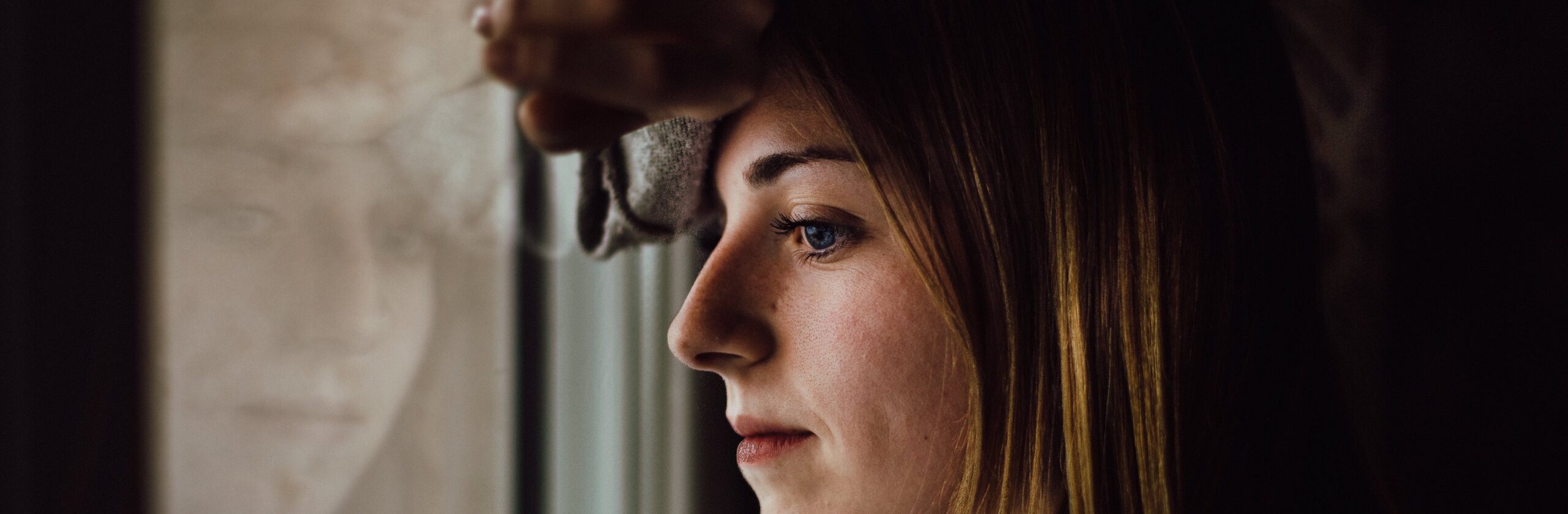 woman looking out window representing alcohol withdrawal timeline symptoms.