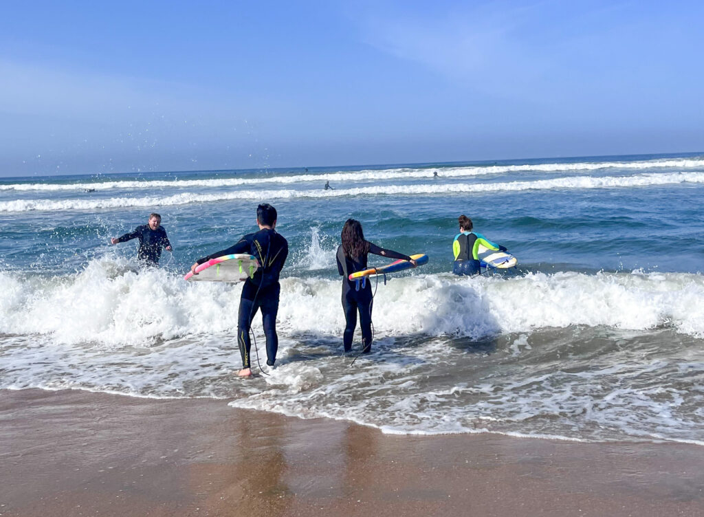 4 people walking out with surfboards to go surfing in California