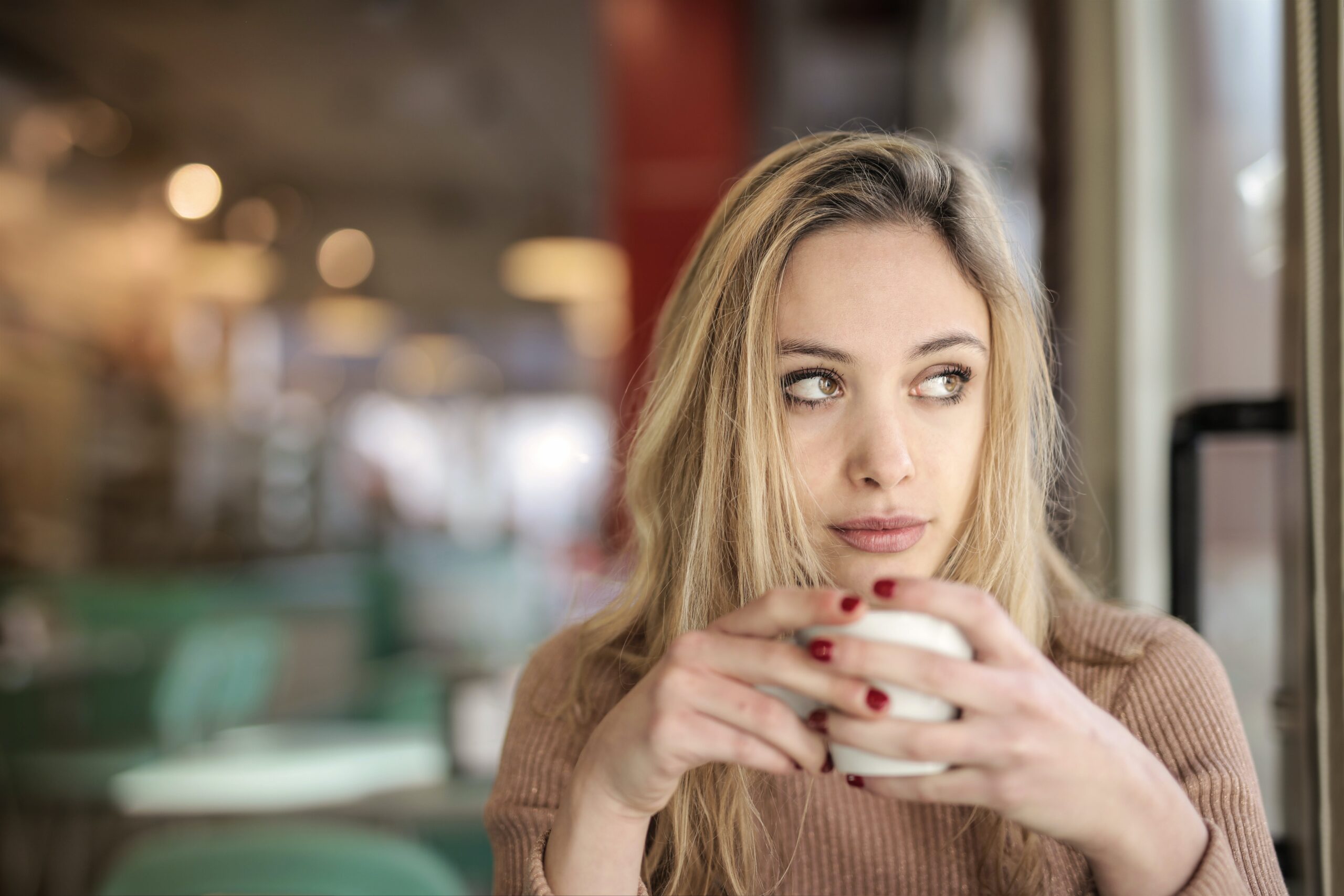 An image of a woman drinking coffee, thinking about all of the reasons to get sober