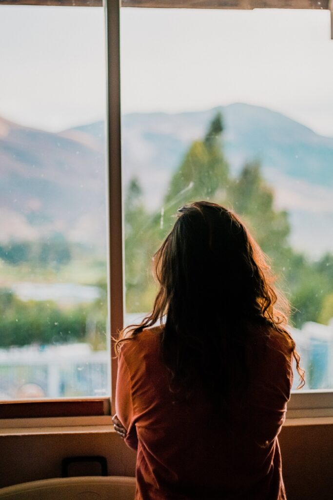 woman looking out a window to represent trauma