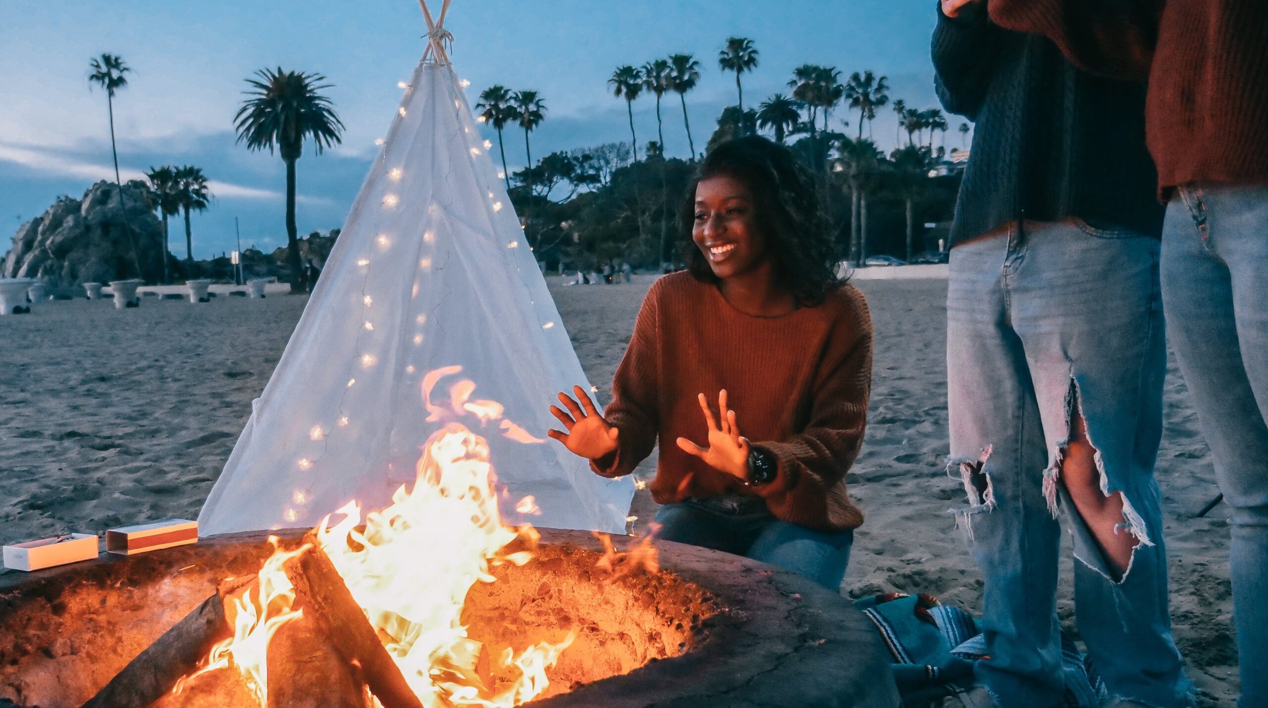 woman enjoying a bonfire on the beach with friends
