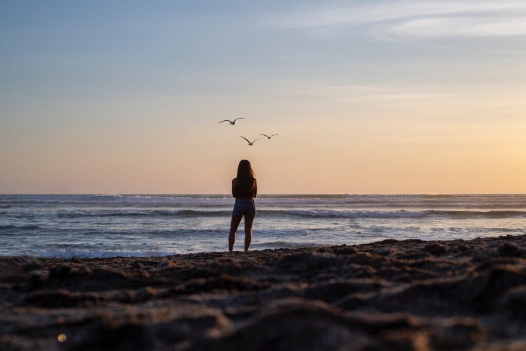 A woman walking on the beach trying to determine how to process trauma