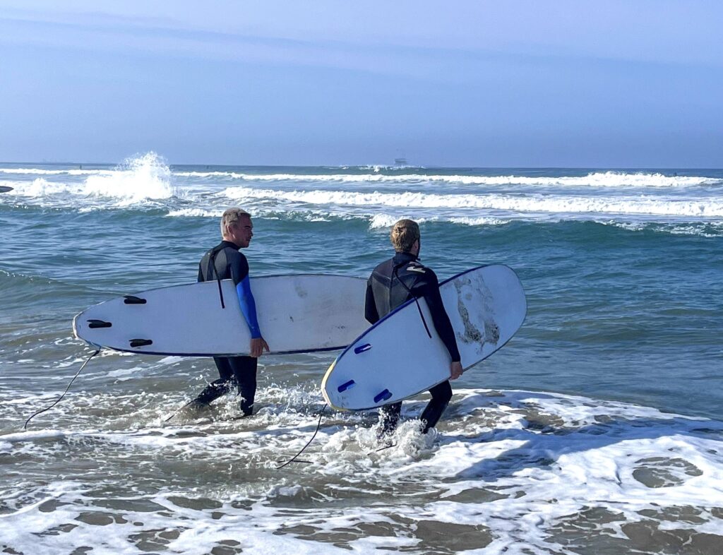 image of two friends surfing near Renaissance Recovery Southern California location
